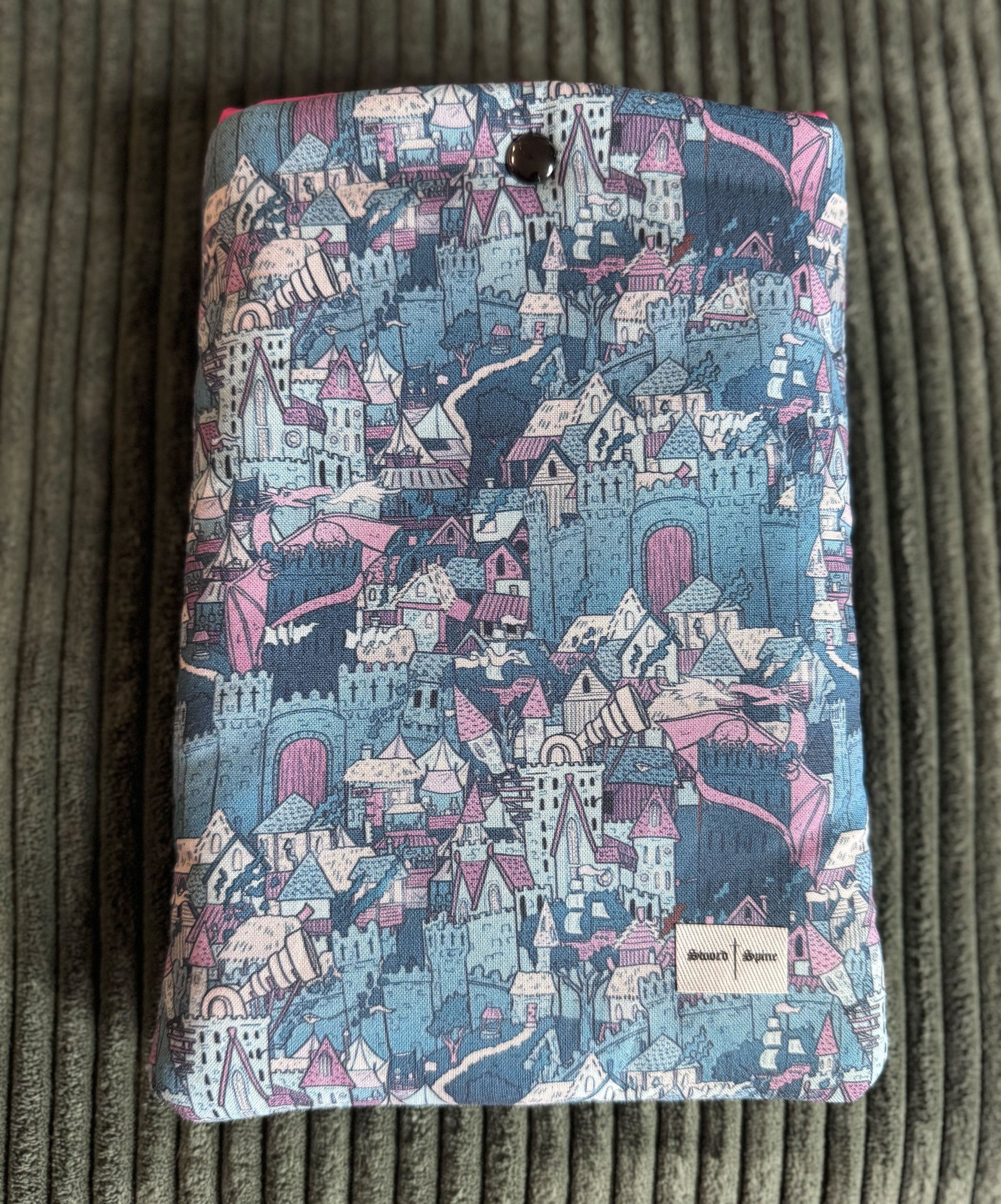 A handmade kindle e-reader sleeve with a castle and dragon pattern in blue.