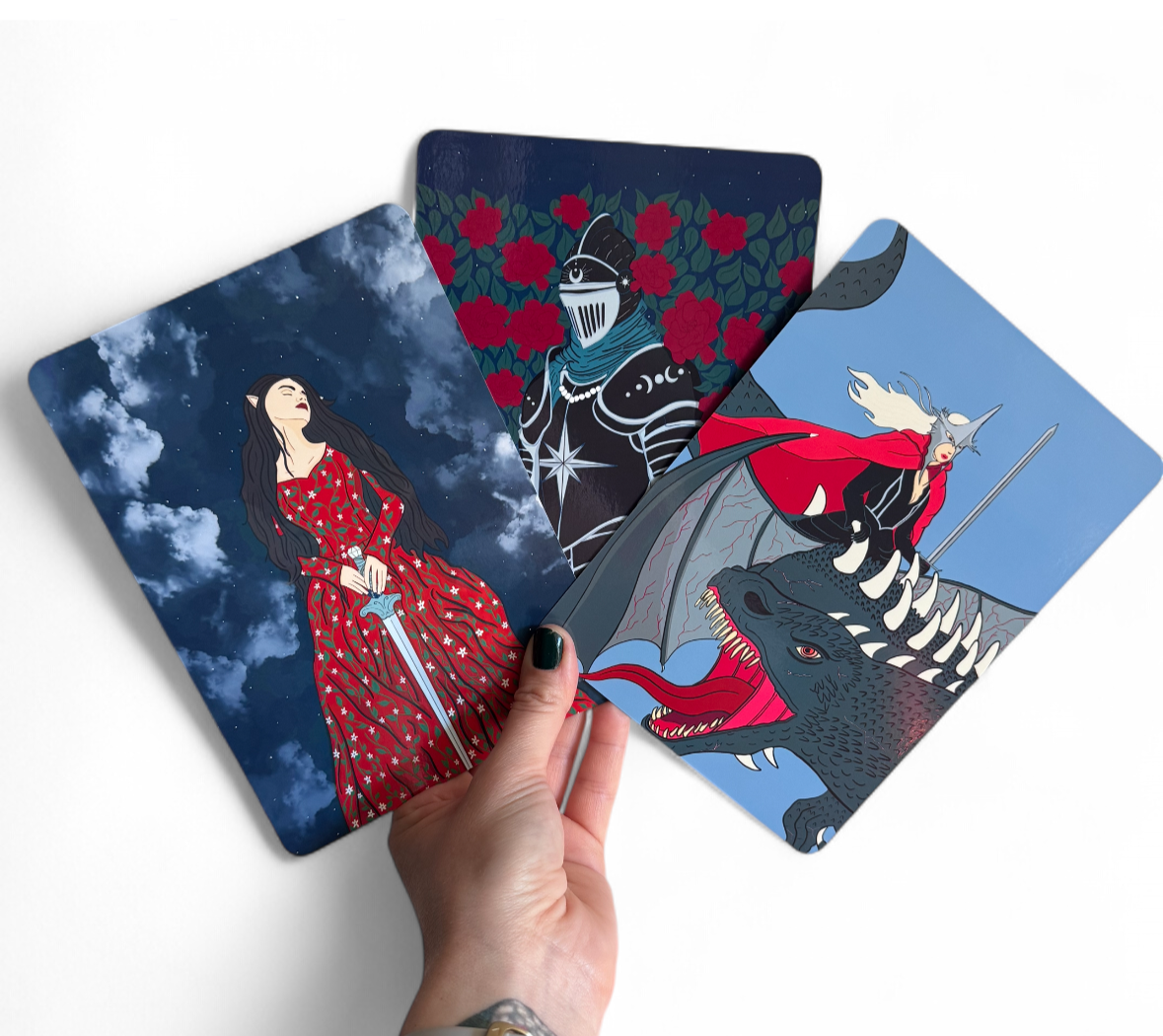 A photo of hand drawn fantasy kindle inserts with dragons, knights, and a fae woman.