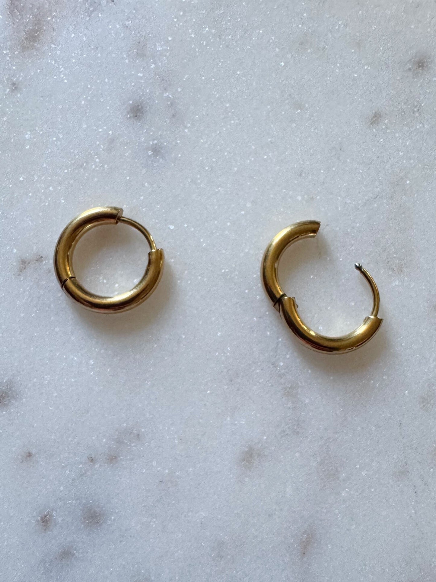 Gold hoop earrings on a marble surface