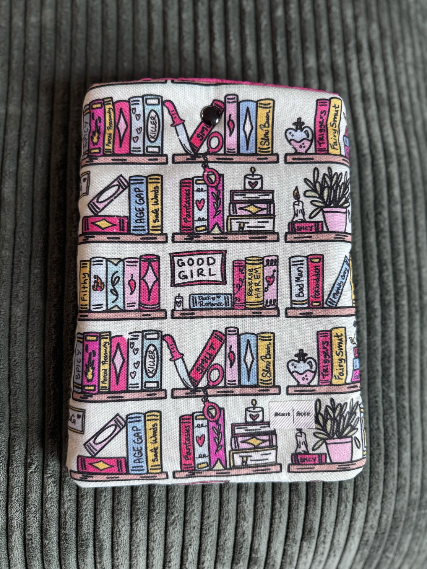 A handmade padded e-reader sleeve with a romance book shelf pattern.