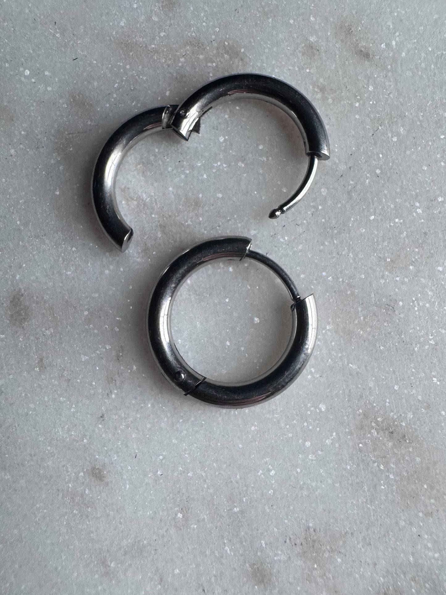 Stainless steel clicker hoops on a marble background.