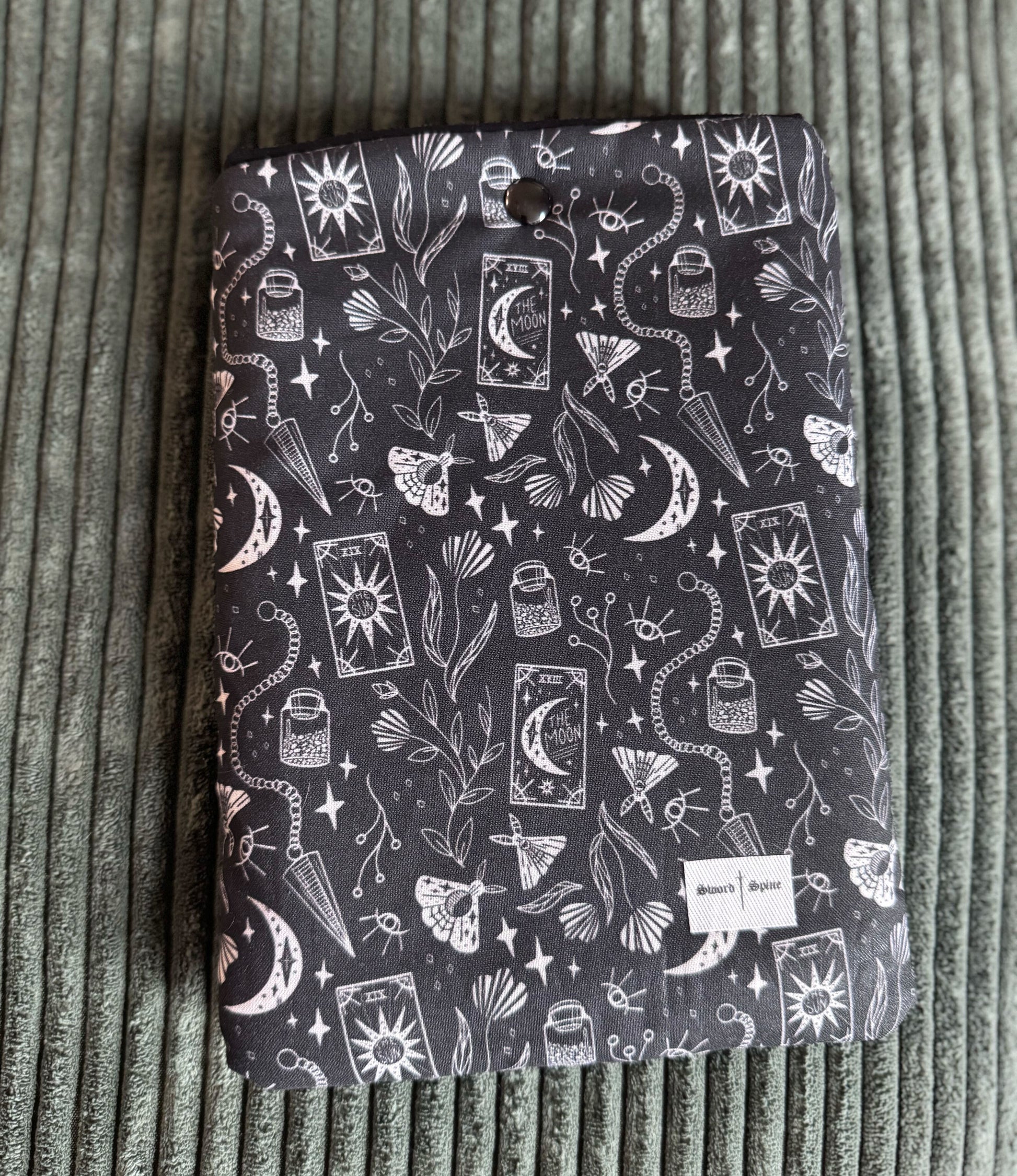 A black and white kindle e-reader sleeve with a pattern of tarot cards and pendulums.