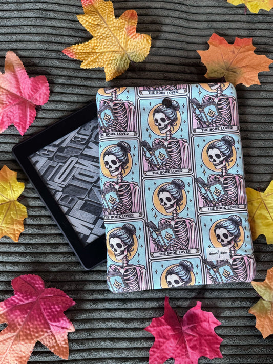 A handmade kindle e-reader sleeve features a repeated pattern of tarot cards with a woman reading.