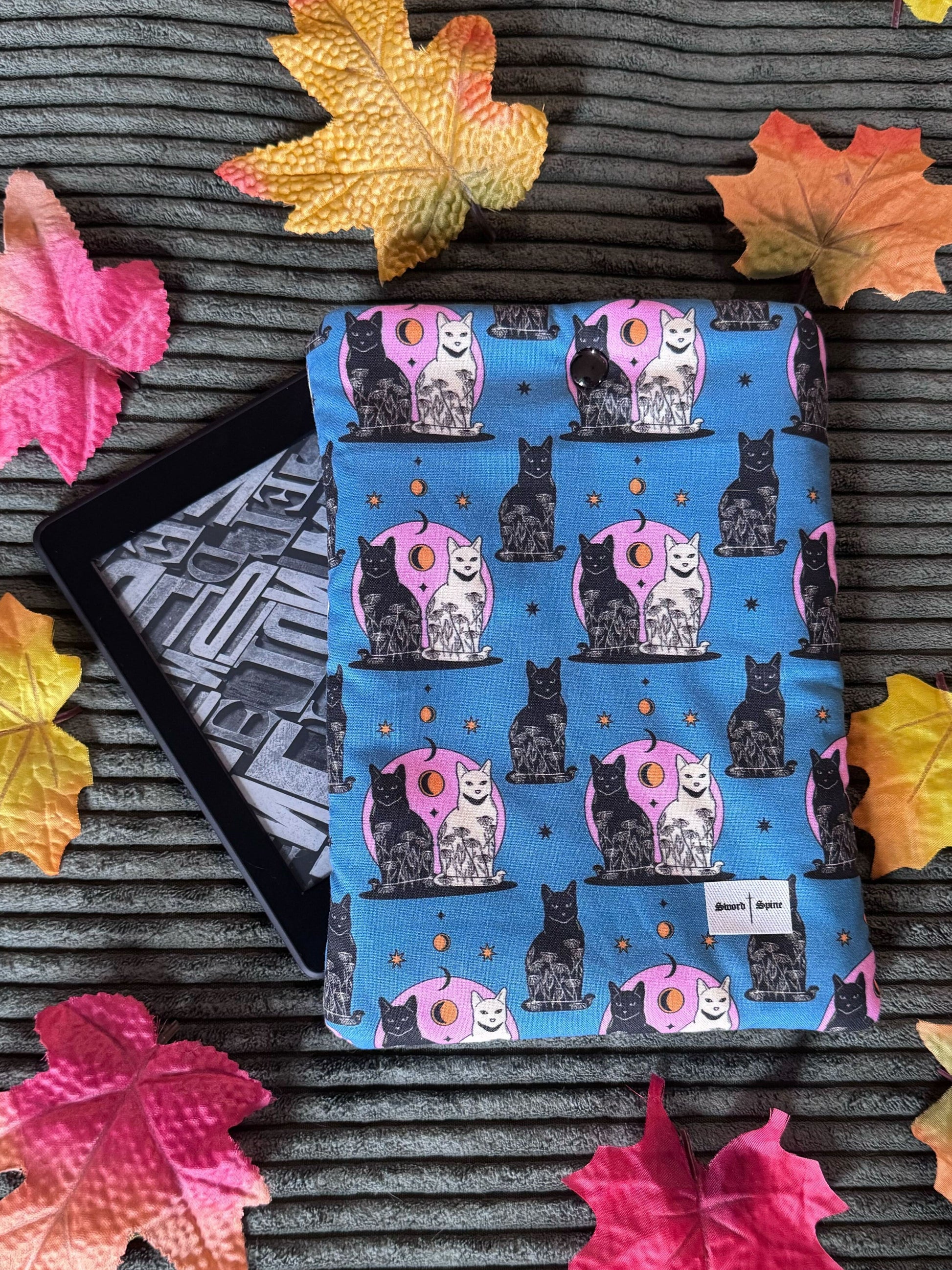 A handmade kindle e-reader sleeve featuring a repeated pattern of black and white cats and crescent moons.