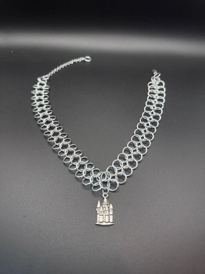 A european weave chainmail choker features a small silver castle pendant.