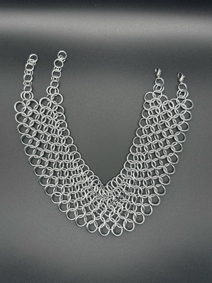 A wide silver chainmail choker with adjustable links rests on a dark background.