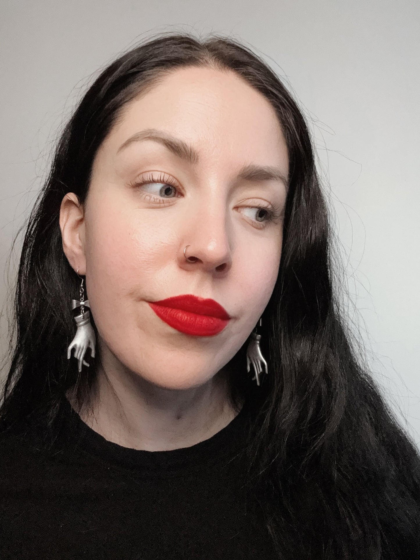 A woman wears a pair of coquette earrings featuring silver victorian mourning hands and bows.