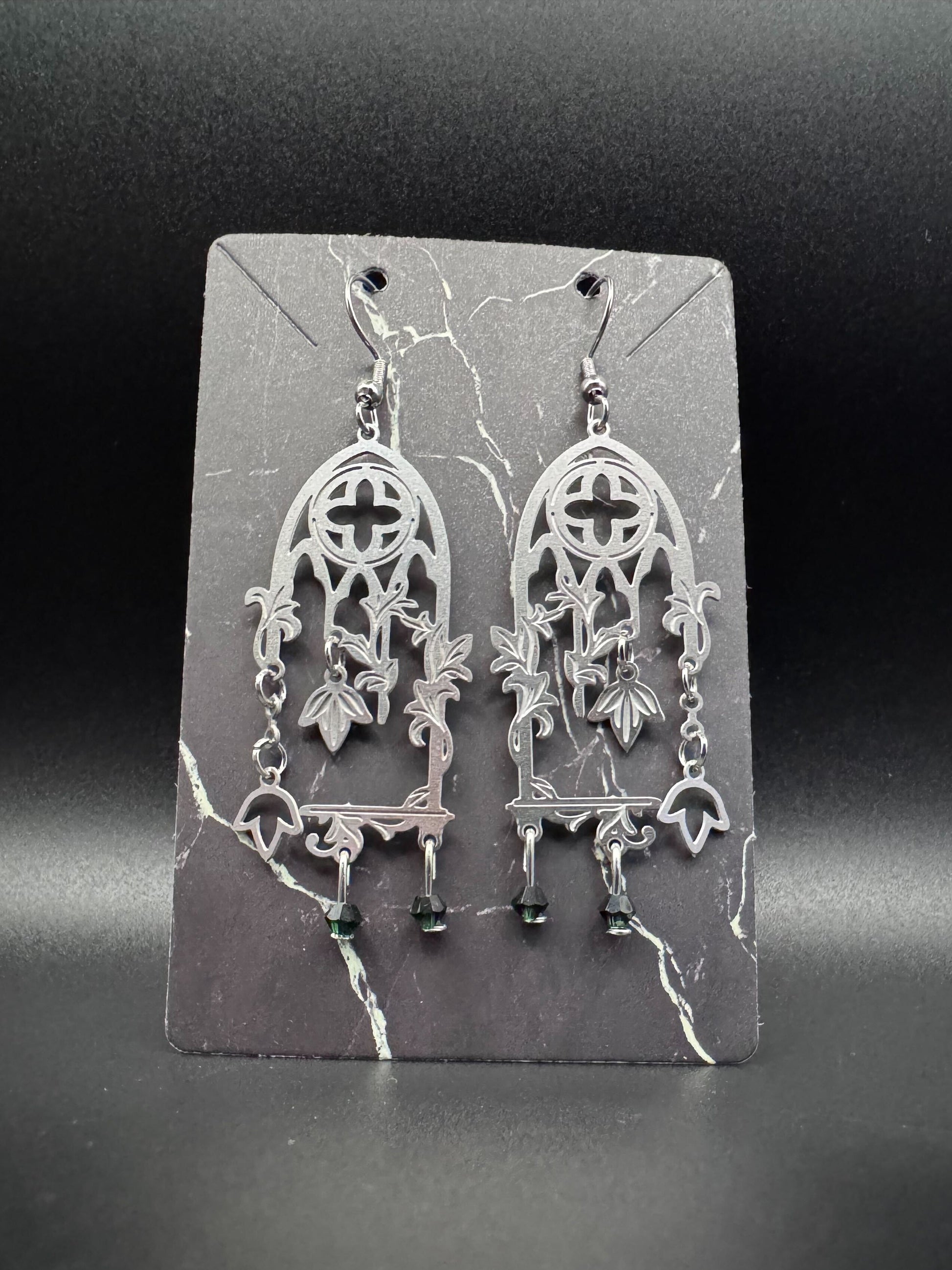 Stainless steel cathedral windows with vines and dark green emeralds.