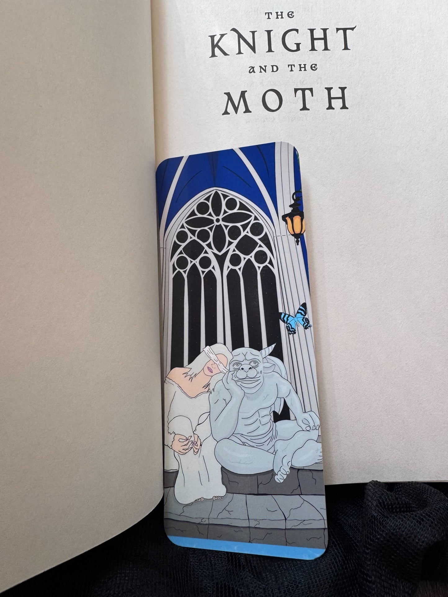 A handmade bookmark rests inside the book The Knight and the Moth and features the main characters, Sybil and Bartholomew.