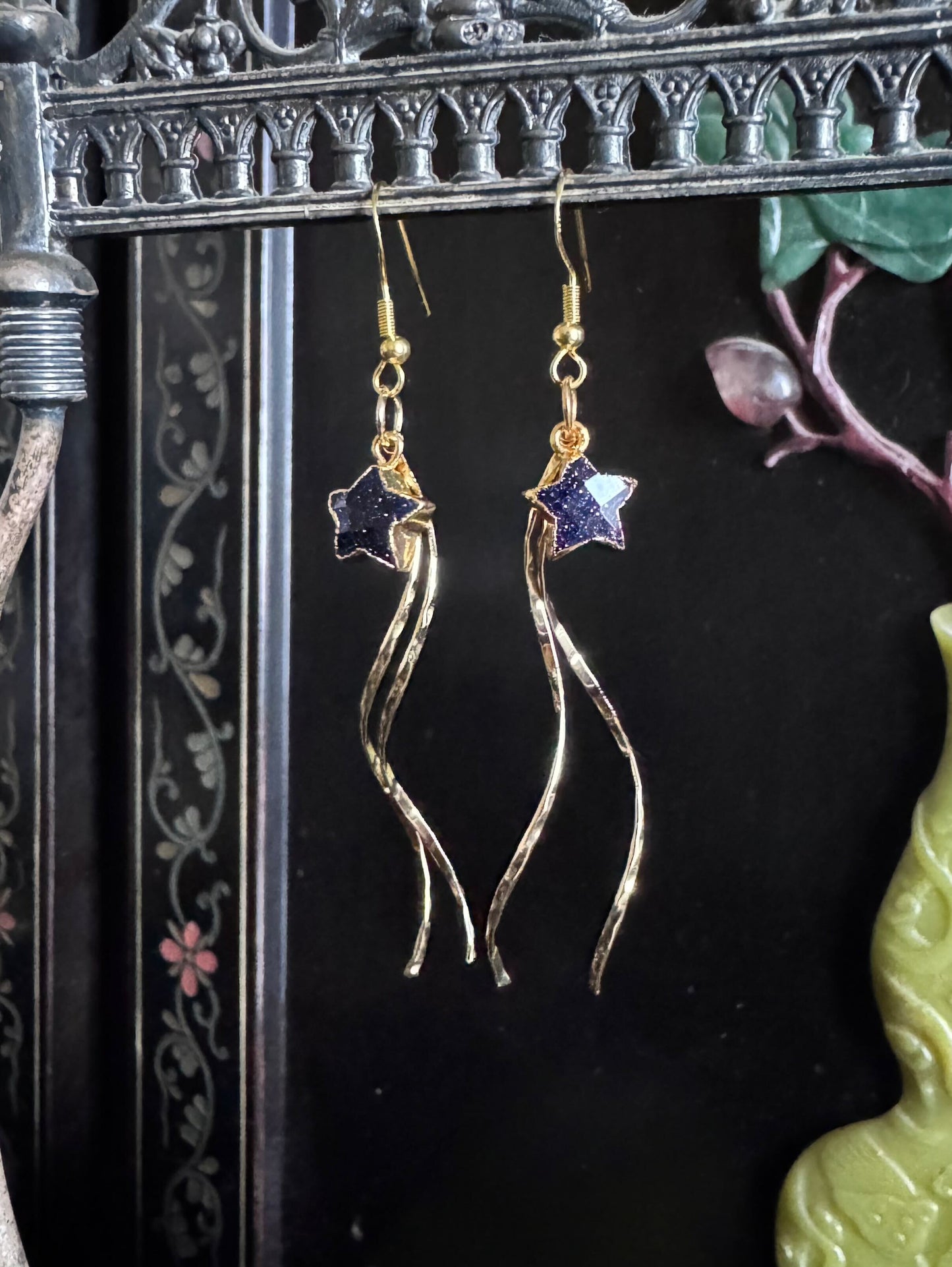 Gold earrings with sunstone stars, dangle with golden threads, giving the illusion of a shooting star.