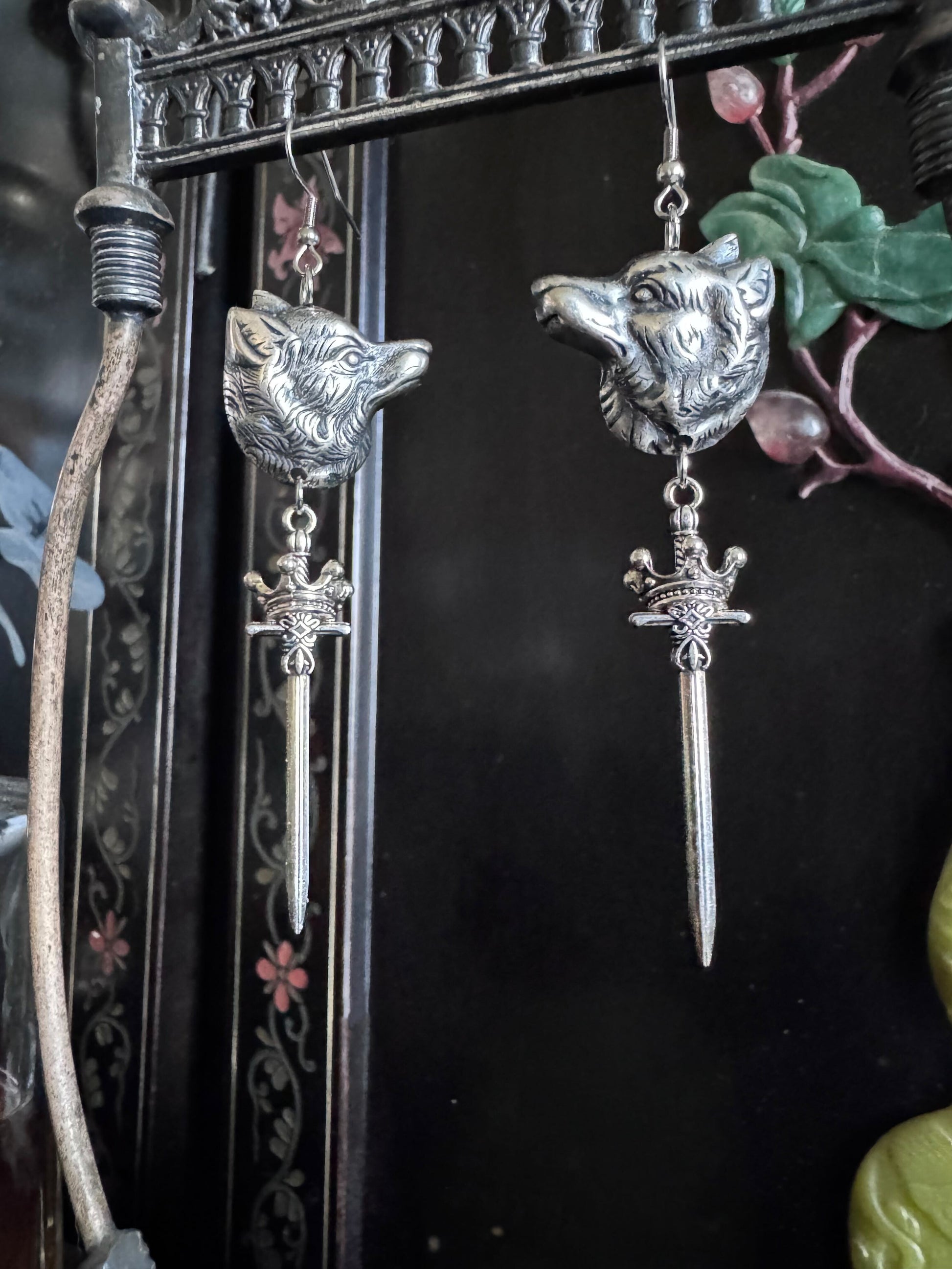 Sterling silver finished wolf heads dangle as a set of earrings with swords and crowns.