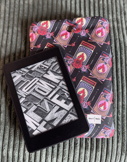 A kindle resting on a handmade e-reader sleeve with a repeating pattern of matchboxes.