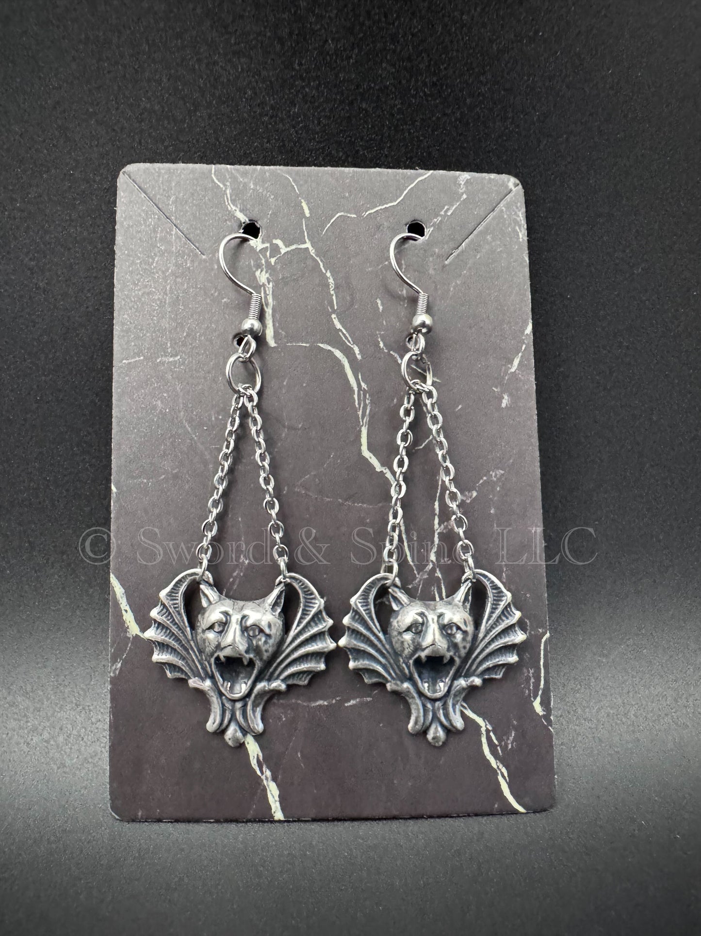 A pair of earrings featuring sterling silver finished gargoyles hanging from chains.