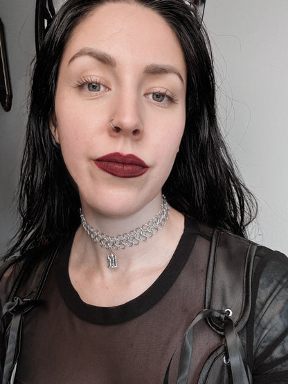 A woman with dark hair wears a European 4 in 1 weave chainmail choker with a castle pendant.